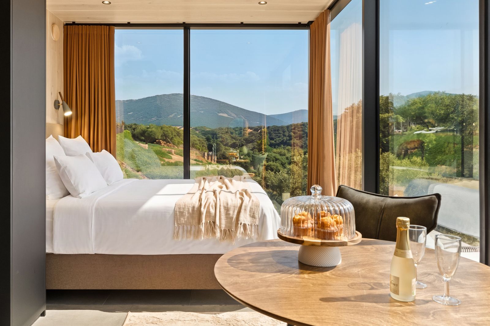 Interior de una Casa Espejo de Cork Valley: cama con vistas al campo y mesa con cava